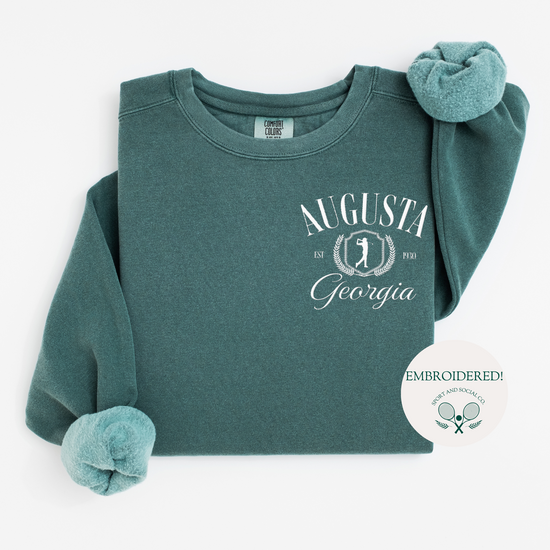 Augusta Georgia embroidered Comfort Colors crewneck sweatshirt with vintage retro golf-inspired design. White embroidery on the left chest pocket area, 4 inches wide, on a soft, garment-dyed pullover.