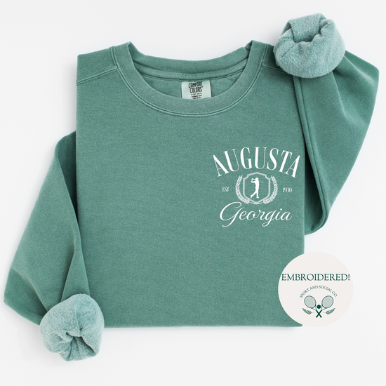 Augusta Georgia embroidered Comfort Colors crewneck sweatshirt with vintage retro golf-inspired design. White embroidery on the left chest pocket area, 4 inches wide, on a soft, garment-dyed pullover.