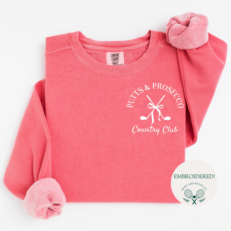 Comfort Colors mid-weight crewneck sweatshirt with 'Putts and Prosecco' embroidered in pocket position, featuring a boho-style bow and crossed golf clubs design.