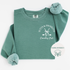 Comfort Colors mid-weight crewneck sweatshirt with 'Putts and Prosecco' embroidered in pocket position, featuring a boho-style bow and crossed golf clubs design.