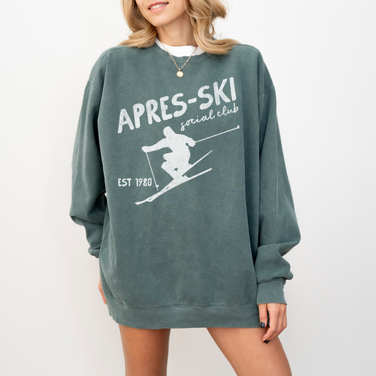 Midweight crewneck sweatshirt with "Après Ski Social Club" text in vintage retro 80s style, featuring a faded grunge look, designed for cozy après-ski vibes.