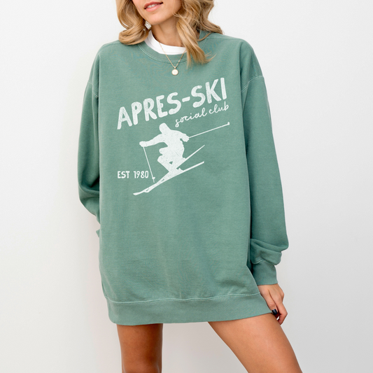 Midweight crewneck sweatshirt with "Après Ski Social Club" text in vintage retro 80s style, featuring a faded grunge look, designed for cozy après-ski vibes.