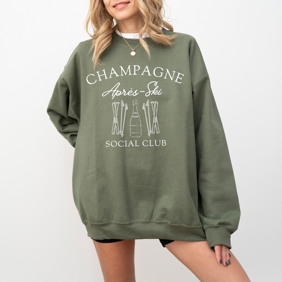 Midweight fleece crewneck sweatshirt with "Champagne Après Ski Social Club" vintage design, perfect for après-ski gatherings and cozy winter wear.