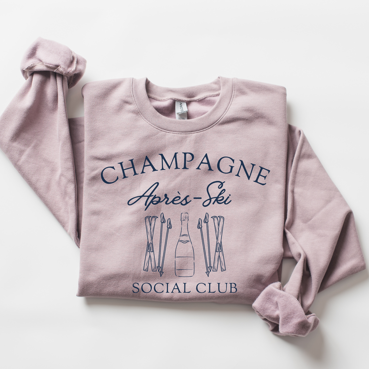 Midweight fleece crewneck sweatshirt with "Champagne Après Ski Social Club" vintage design, perfect for après-ski gatherings and cozy winter wear.