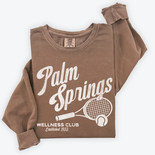 Palm Springs Wellness Club crewneck sweatshirt with a retro tennis racquet graphic in vintage grunge print, perfect for athleisure or casual wear.