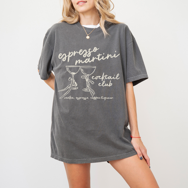 Unisex Comfort Colors short sleeve T-shirt with boho-style Espresso Martini print. Features retro martini glasses adorned with bows, in a faded vintage-inspired design on soft cotton fabric.