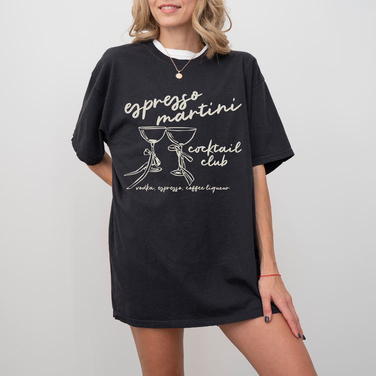 Unisex Comfort Colors short sleeve T-shirt with boho-style Espresso Martini print. Features retro martini glasses adorned with bows, in a faded vintage-inspired design on soft cotton fabric.