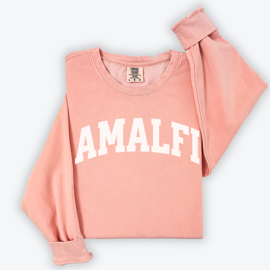 Flatlay image of a lightweight Comfort Colors sweatshirt in soft cotton with 'Amalfi' printed in a sporty, university-style font across the chest. The relaxed, casual fit and vintage-inspired design give the sweatshirt a cozy, well-loved look