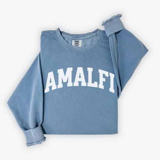 Flatlay image of a lightweight Comfort Colors sweatshirt in soft cotton with 'Amalfi' printed in a sporty, university-style font across the chest. The relaxed, casual fit and vintage-inspired design give the sweatshirt a cozy, well-loved look