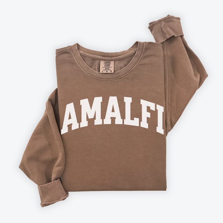 Flatlay image of a lightweight Comfort Colors sweatshirt in soft cotton with 'Amalfi' printed in a sporty, university-style font across the chest. The relaxed, casual fit and vintage-inspired design give the sweatshirt a cozy, well-loved look