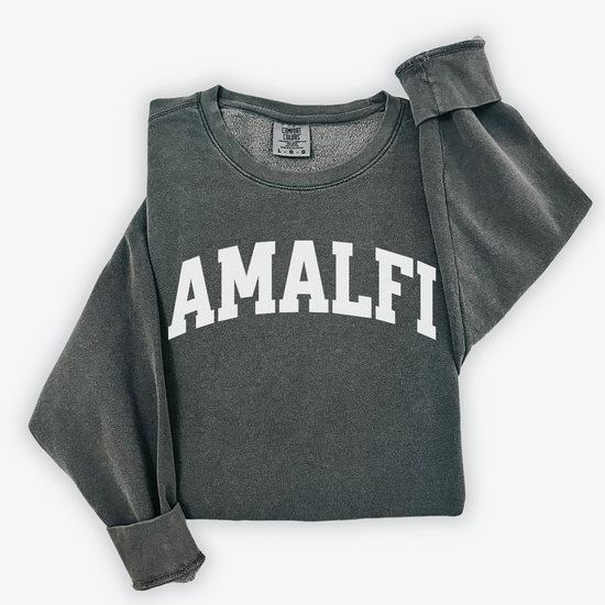 Flatlay image of a lightweight Comfort Colors sweatshirt in soft cotton with 'Amalfi' printed in a sporty, university-style font across the chest. The relaxed, casual fit and vintage-inspired design give the sweatshirt a cozy, well-loved look