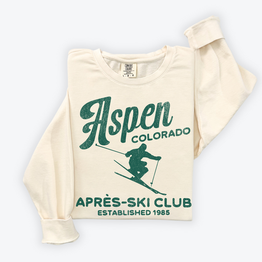 Unisex lightweight cotton Comfort Colors crewneck sweatshirt with "Aspen Après Ski Club" in vintage retro grunge style print, designed for men and women