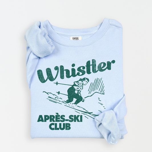 Lightweight cotton crewneck sweatshirt with "Whistler Après Ski Club" in vintage retro style, featuring a graphic of a woman skiing, perfect for après-ski and winter adventures.