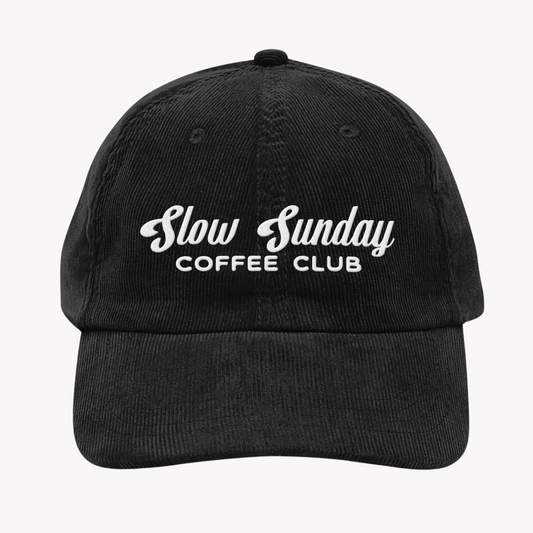 A vintage-style corduroy cap with "Slow Sunday Coffee Club" embroidered on the front, shown in soft, textured fabric with an adjustable strap.