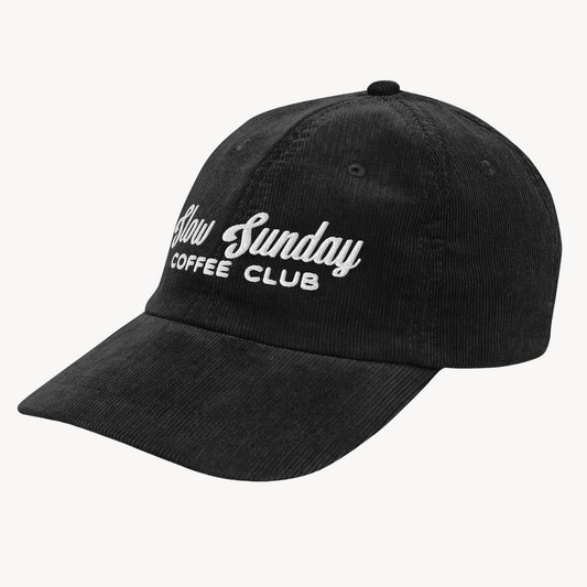 A vintage-style corduroy cap with "Slow Sunday Coffee Club" embroidered on the front, shown in soft, textured fabric with an adjustable strap.