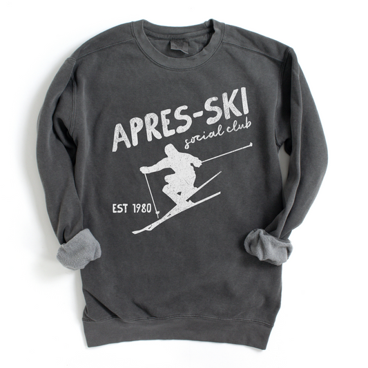 Midweight crewneck sweatshirt with "Après Ski Social Club" text in vintage retro 80s style, featuring a faded grunge look, designed for cozy après-ski vibes.