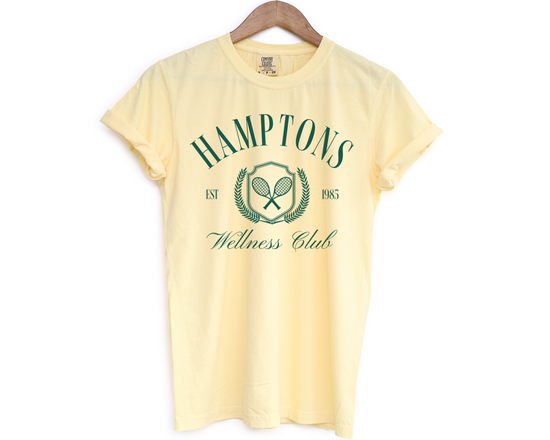 Hamptons Wellness Club short sleeve t-shirt with retro tennis graphics, worn by a model, yellow color with green print