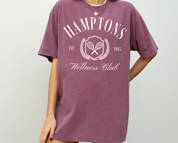 Hamptons Wellness Club short sleeve t-shirt with retro tennis graphics, worn by a model, purple shirt with white print