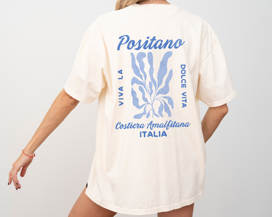 Comfort Colors short sleeve t-shirt featuring a whimsical coastal design on the back, "Viva la Dolce Vita" text, and a faded vintage grunge look in coastal blue, ideal for summer and travel vibes.