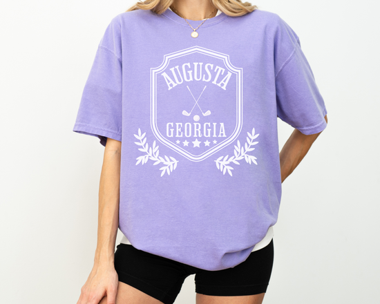 Model wearing a retro style Augusta, Georgia short sleeve t-shirt with vintage golf-inspired graphics, Purple Color Shirt