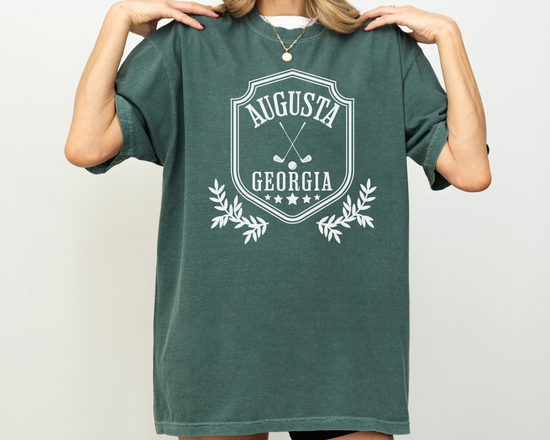 Model wearing a retro style Augusta, Georgia short sleeve t-shirt with vintage golf-inspired graphics, Green Shirt