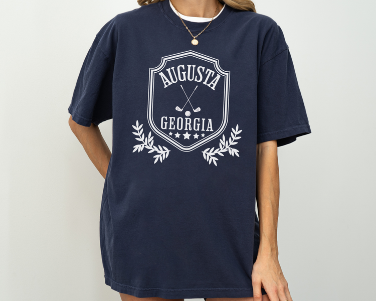 Model wearing a retro style Augusta, Georgia short sleeve t-shirt with vintage golf-inspired graphics, Navy Color Shirt