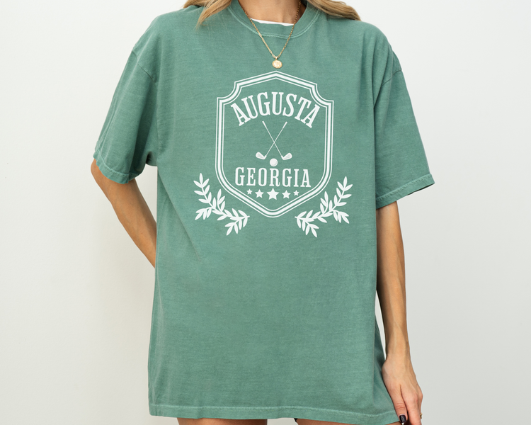 Model wearing a retro style Augusta, Georgia short sleeve t-shirt with vintage golf-inspired graphics, Green Shirt