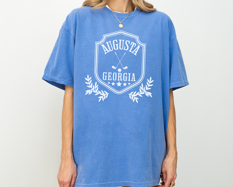 Model wearing a retro style Augusta, Georgia short sleeve t-shirt with vintage golf-inspired graphics, Blue Color Shirt