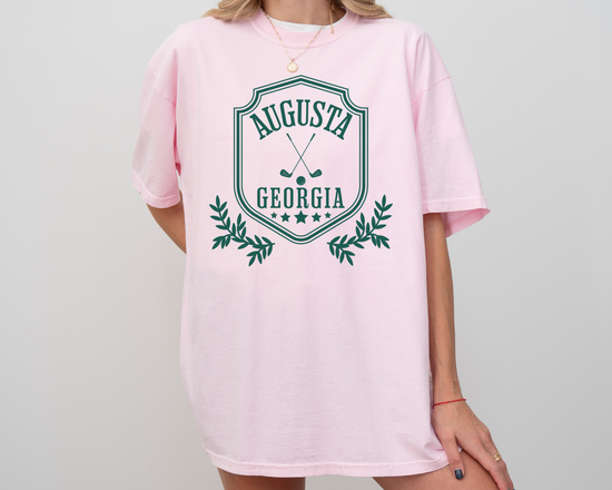 Model wearing a retro style Augusta, Georgia short sleeve t-shirt with vintage golf-inspired graphics, Light Pink Color Shirt